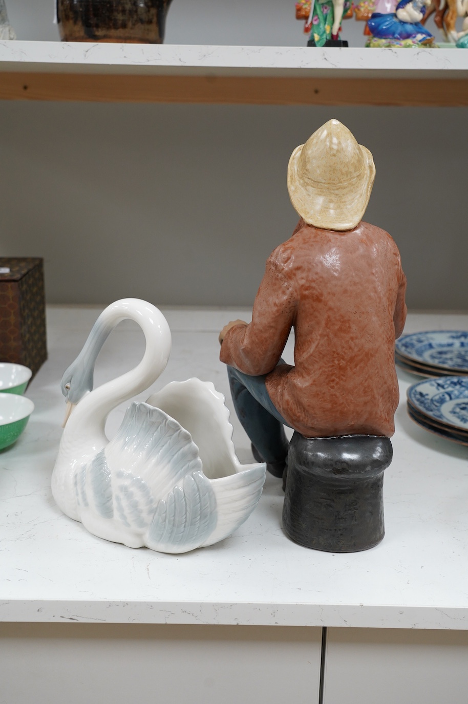 A large Nao seated figure of a fisherman and a similar swan, largest 41cm high. Condition - good